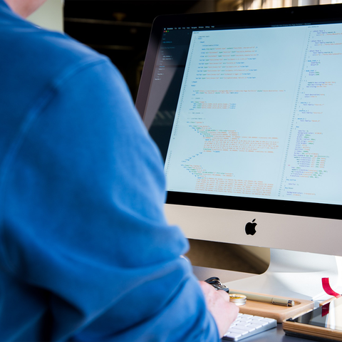 A support engineer reviewing front-end code on a large monitor